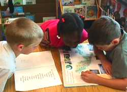 Primary students with email & geography book to locate global peers.